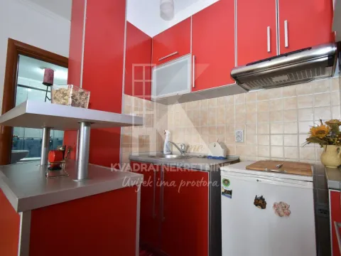 Kitchen with bright red cabinets and a small refrigerator. - image 7
