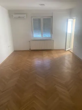 Prazna soba sa parketom, klima uređajem i prozorom. - image 3