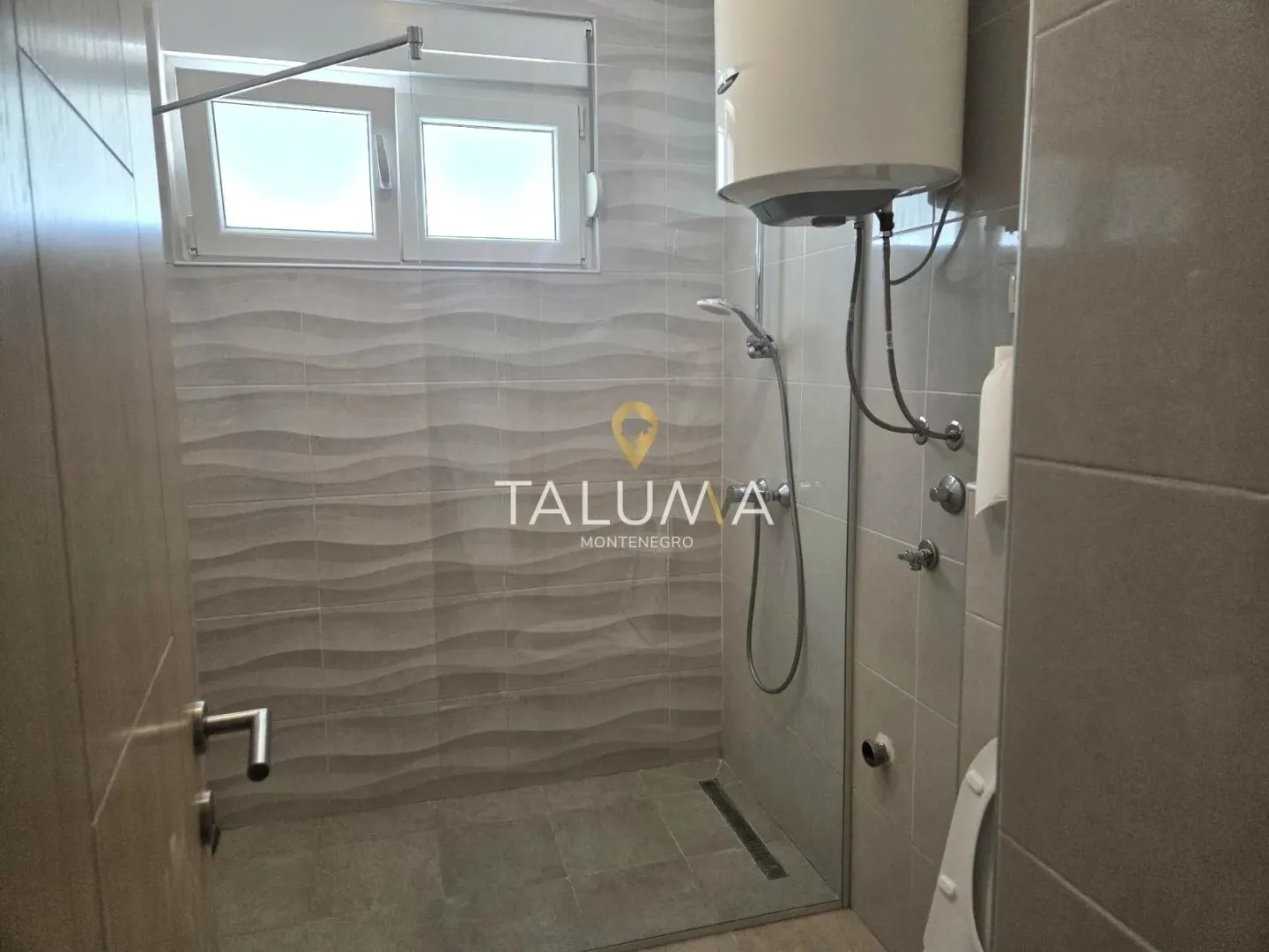 Bathroom with a walk-in shower tiled in grey.