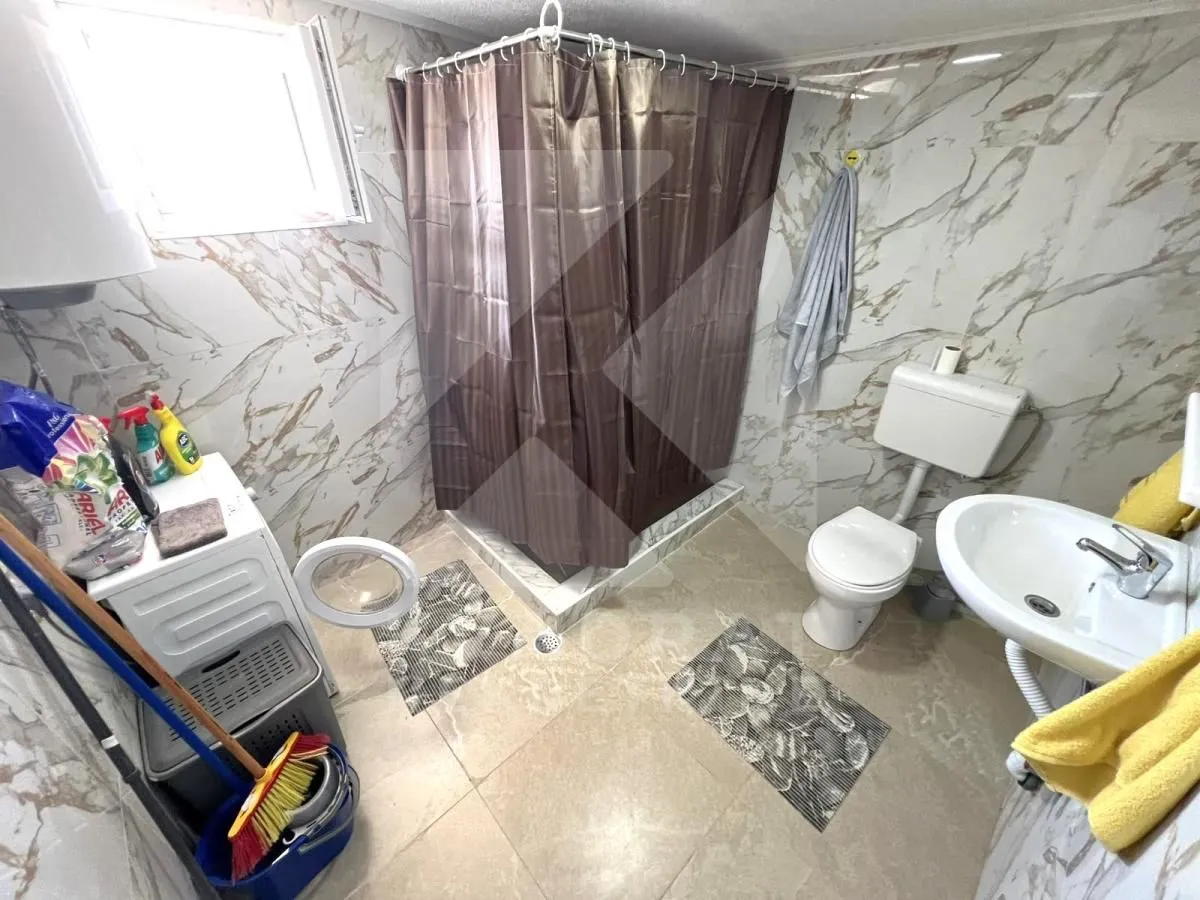 Bathroom with a shower cabin, toilet, washbasin, and washing machine.