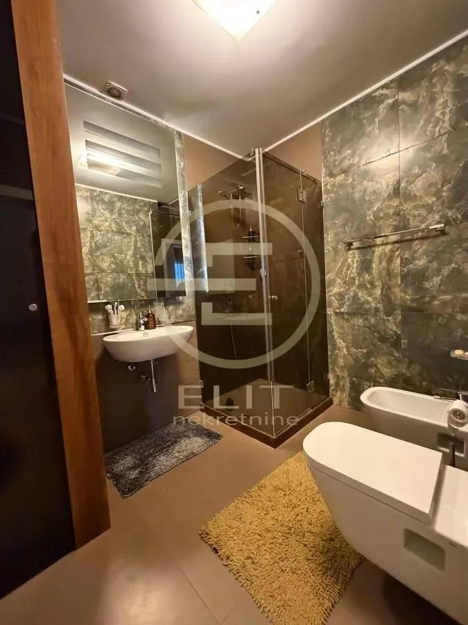 Moderno kupatilo sa tuš kabinom, umivaonikom i sanitarijama.