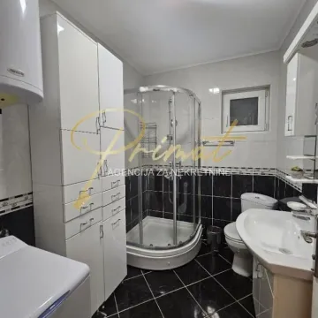 Kupatilo opremljeno tuš kabinom, umivaonikom, WC šoljom i belim elementima za odlaganje. - image 6