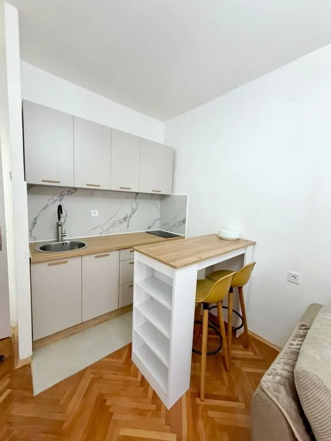 Manja kuhinja sa elementima u bež boji i šankom za ručavanje.