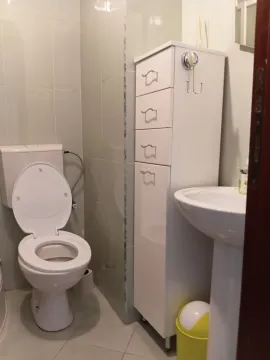 Manje kupatilo sa toaletom, umivaonikom i bijelim ormarićem. - image 8
