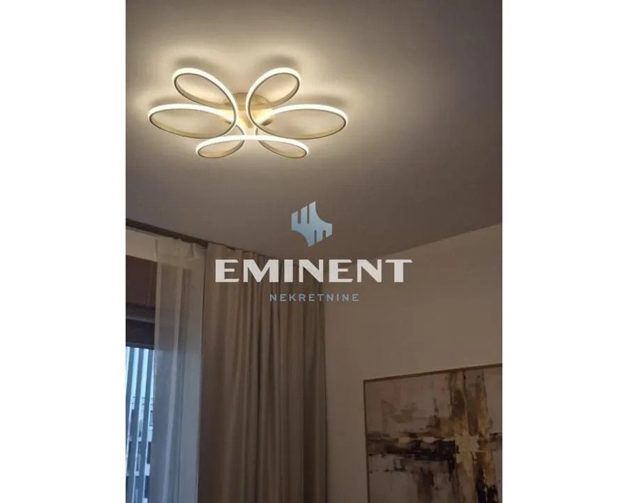 Detalj enterijera sa modernom plafonskom rasvetom i zavesama.
