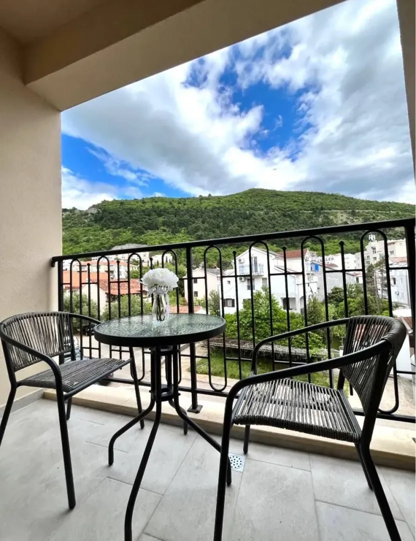 Covered balcony with seating set and view of the settlement.