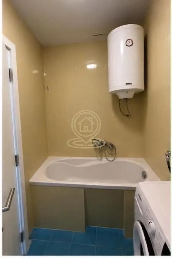Bathroom with a bathtub, water heater, and washing machine.