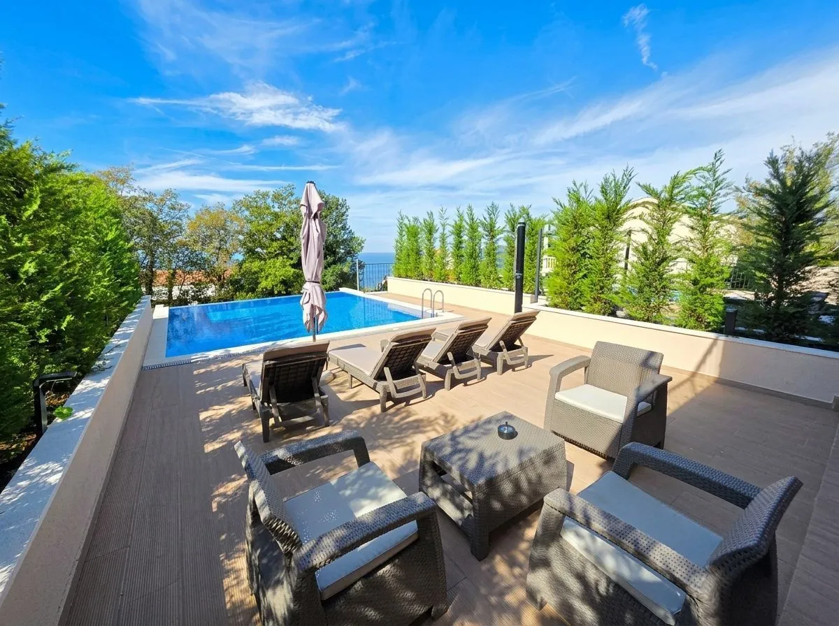 Terrace with a swimming pool, sun loungers and seating furniture.
