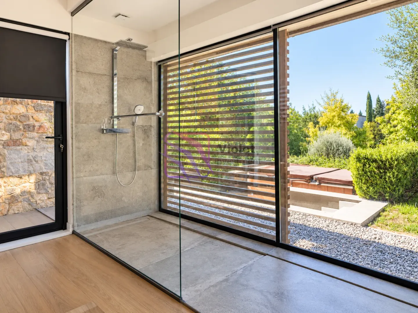 Modern bathroom with a glass shower enclosure and a view of the yard.