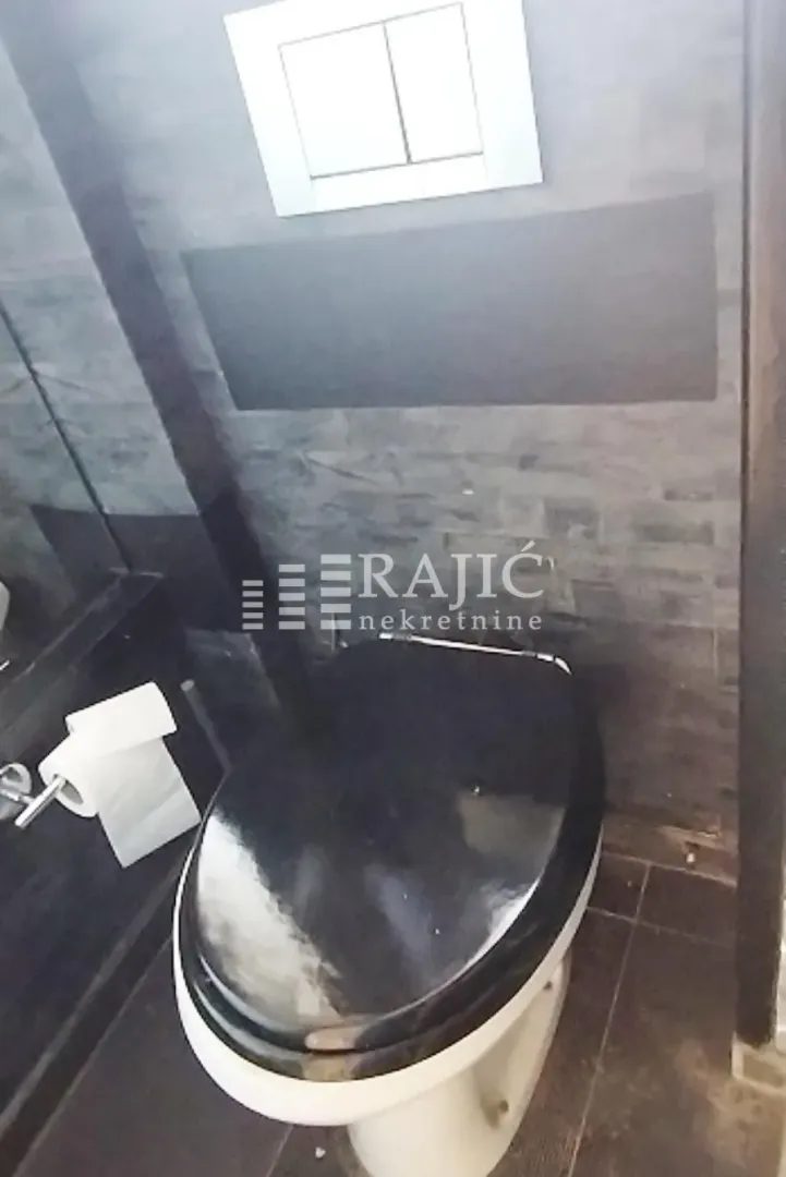 Modernly equipped bathroom with dark tiles and a black toilet bowl.