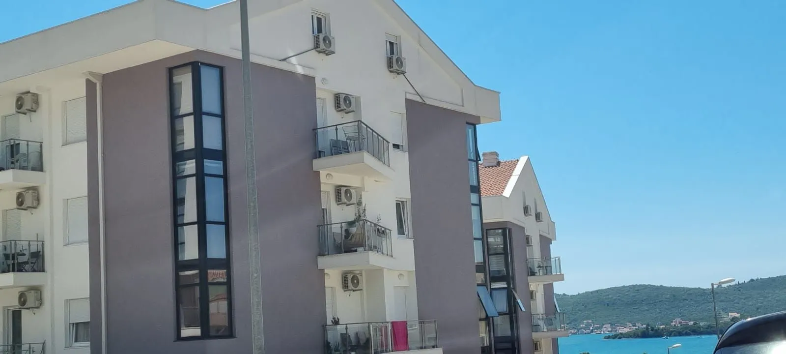 Spoljašnji izgled stambene zgrade sa balkonom i pogledom na more.