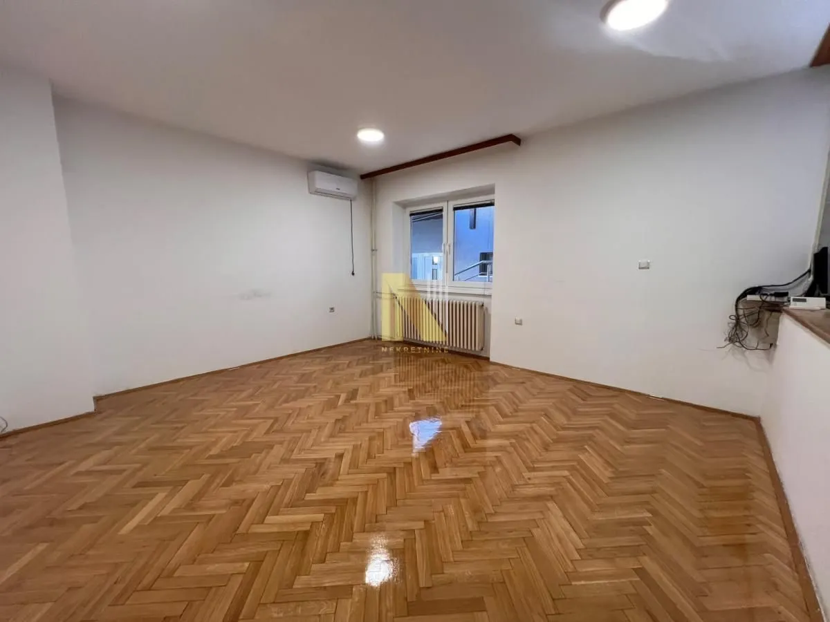 Prazna soba sa parketom i belim zidovima.