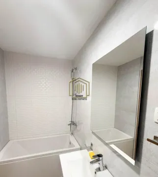 Modernly equipped bathroom with a bathtub, washbasin, and large mirror. - image 8