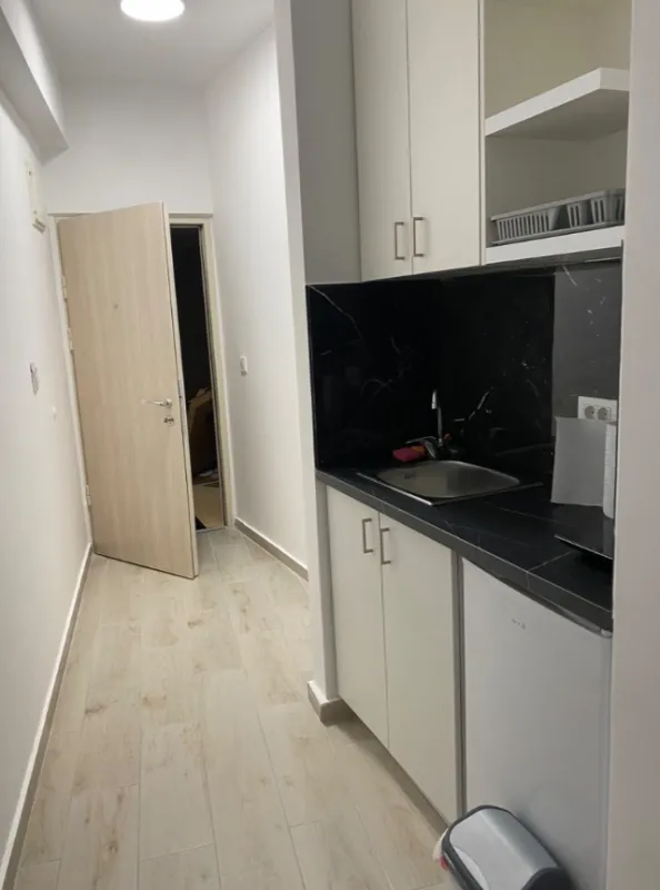 Manja čajna kuhinja u hodniku sa sudoperom i radnom površinom.