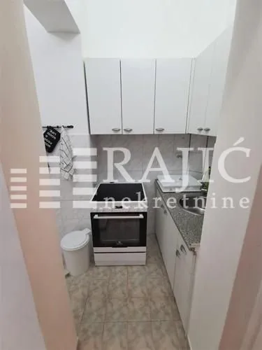 Small white kitchen with a stove and sink.
