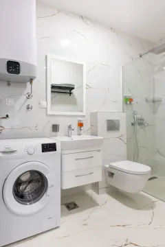 Moderne opremljeno kupatilo sa bijelim keramičkim pločicama, umivaonikom, tuš kabinom i veš mašinom. - image 8