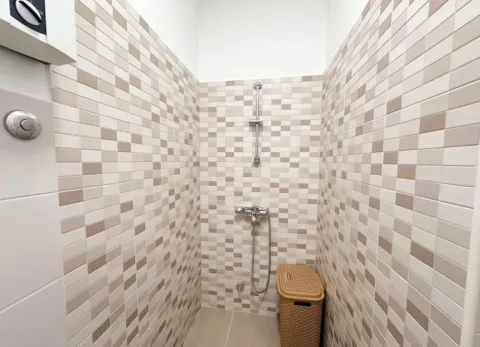 Bathroom lined with mosaic tiles featuring a shower enclosure. - image 7