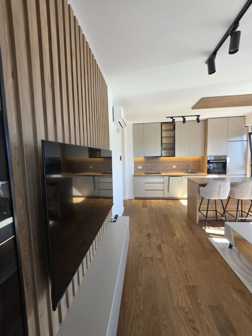 Modern kitchen with a breakfast bar and wooden wall paneling in the living area.