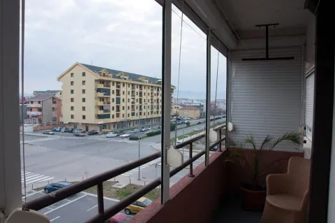 Glazed balcony with a chair and a neighborhood view. - image 8