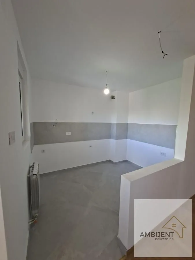 Prazna neopremljena prostorija sa belim zidovima i pločicama.