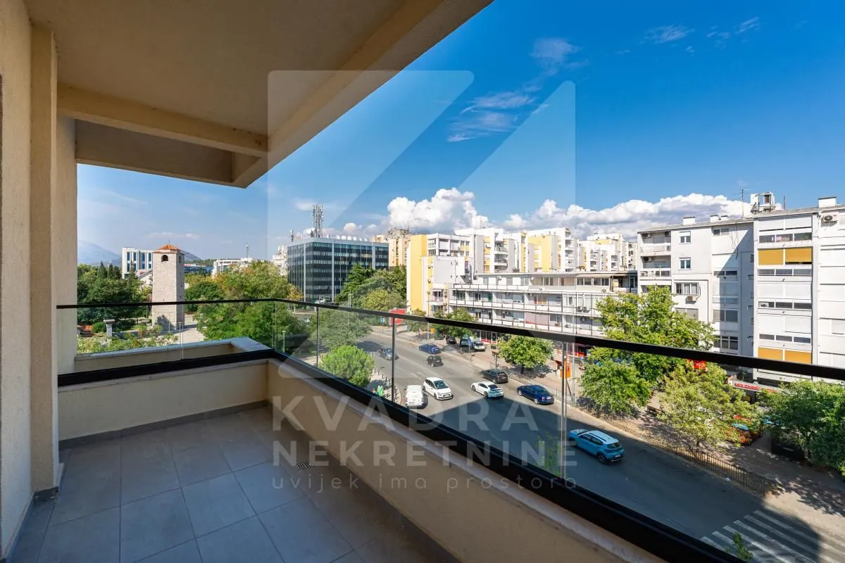 Spacious balcony with a glass railing and a view of the city streetscape.