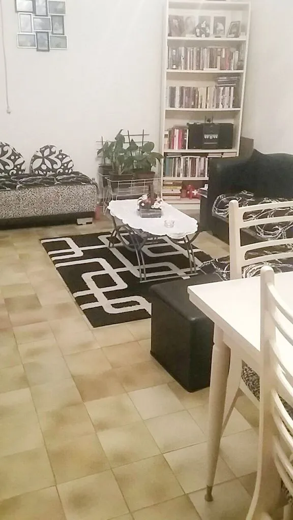 Dnevna soba sa garniturom, policom za knjige i trpezarijskim stolom.