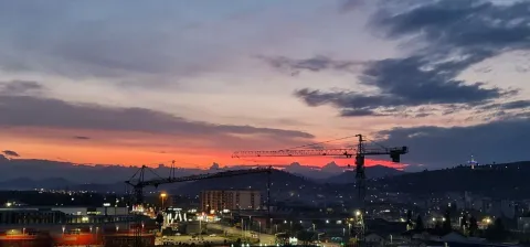 Pogled na grad i zalazak sunca sa građevinskim kranovima u daljini. - image 8