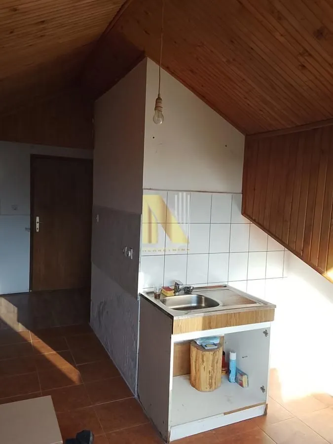 Manja kuhinja sa sudoperom u potkrovlju sa drvenom lamperijom.