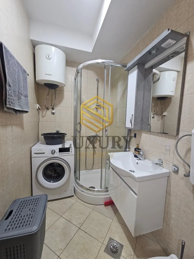 Small bathroom with a shower cabin, sink, washing machine, and water heater.