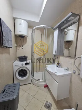 Small bathroom with a shower cabin, sink, washing machine, and water heater. - image 4