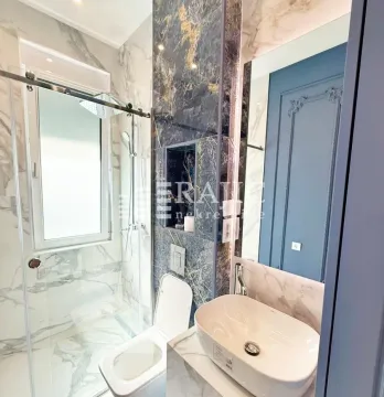 Modernly equipped bathroom with a shower cabin, washbasin, and marble tiles. - image 15