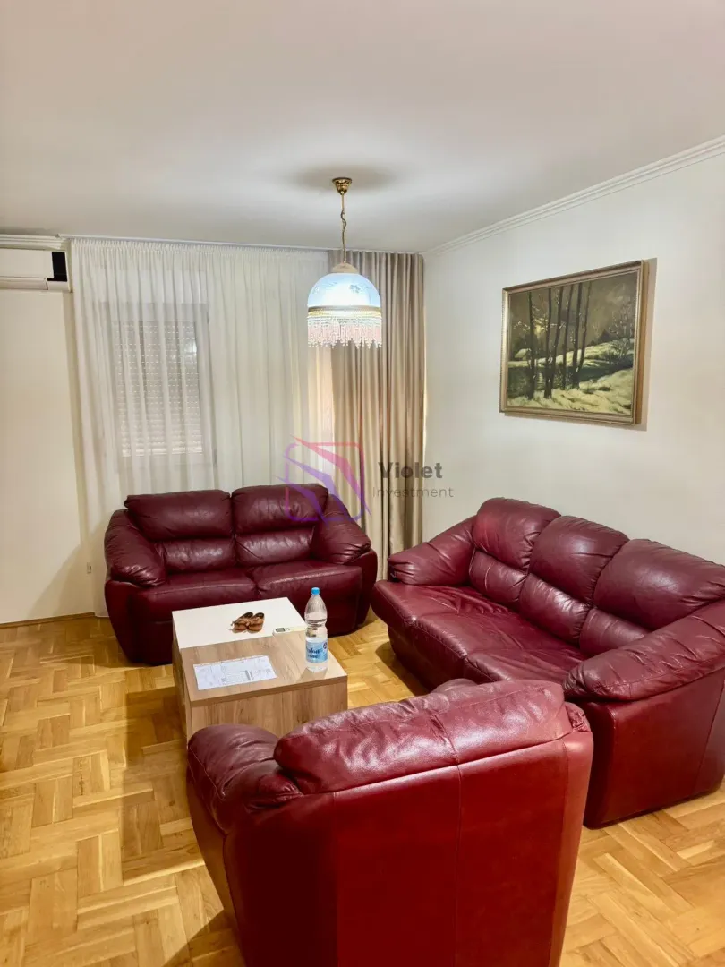 Living room with leather sofas, coffee table and parquet flooring.
