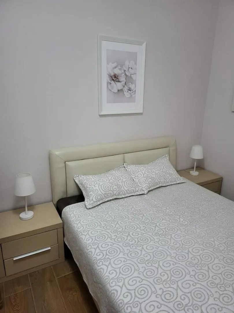 Uređena spavaća soba sa bračnim krevetom, noćnim stočićima i lampama.