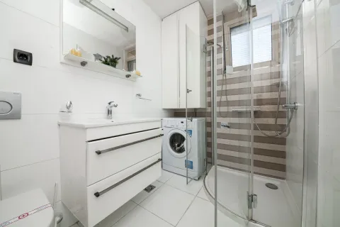 Svijetlo opremljeno kupatilo sa tuš kabinom, umivaonikom i veš mašinom. - image 7
