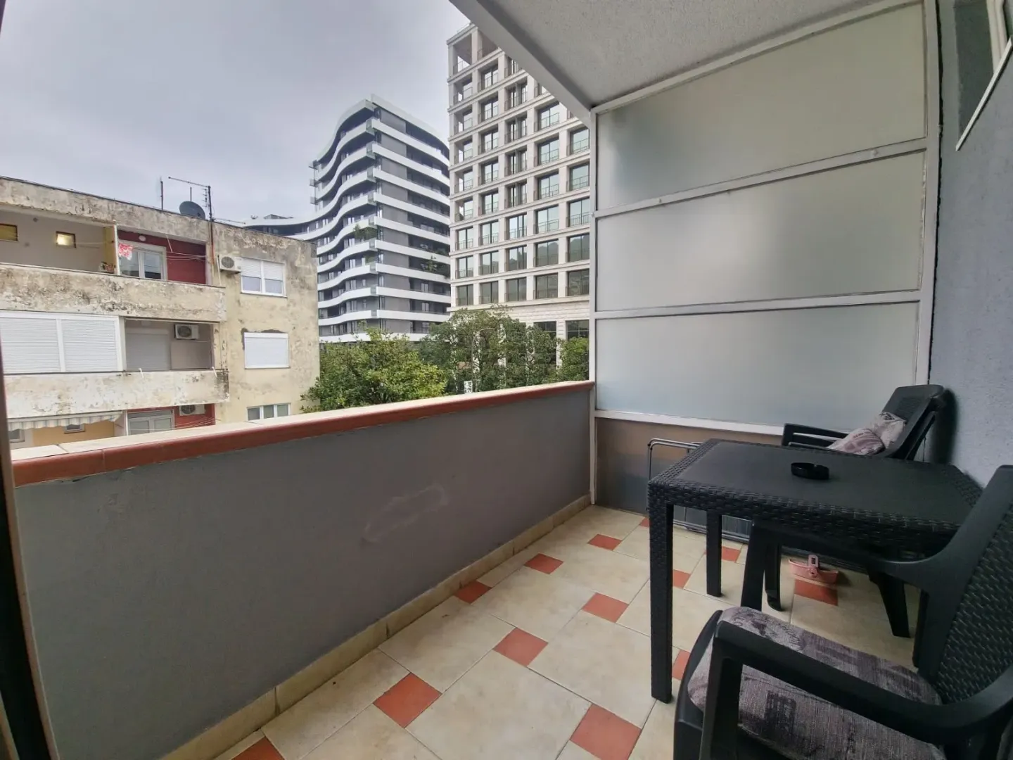 Covered balcony with outdoor seating and a view of the city.