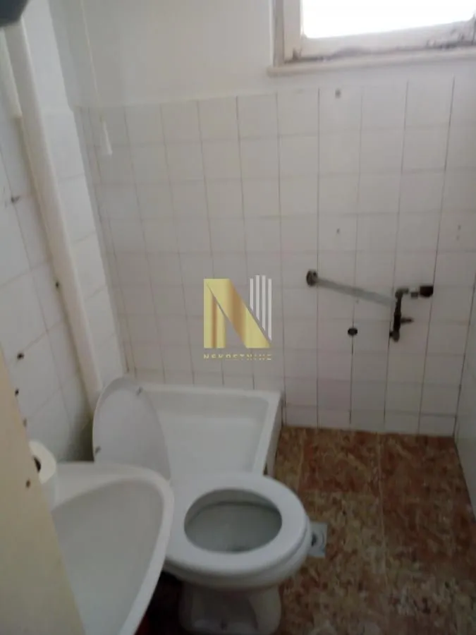 Manje kupatilo sa osnovnim sanitarijama i belim zidnim pločicama.