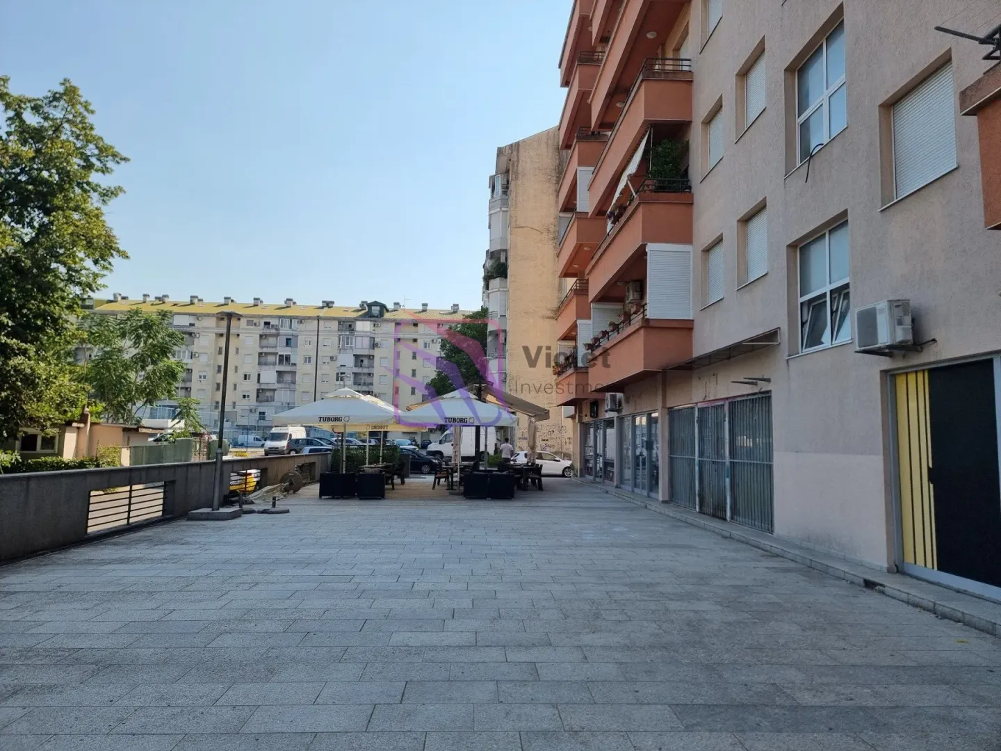 View of the paved plateau in front of the apartment building with an outdoor cafe.
