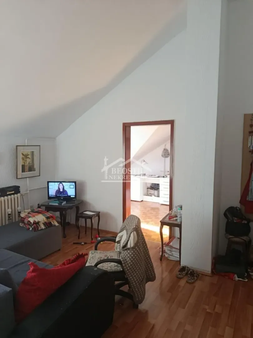 Dnevni boravak sa garniturom i pogledom na susednu prostoriju kroz vrata.
