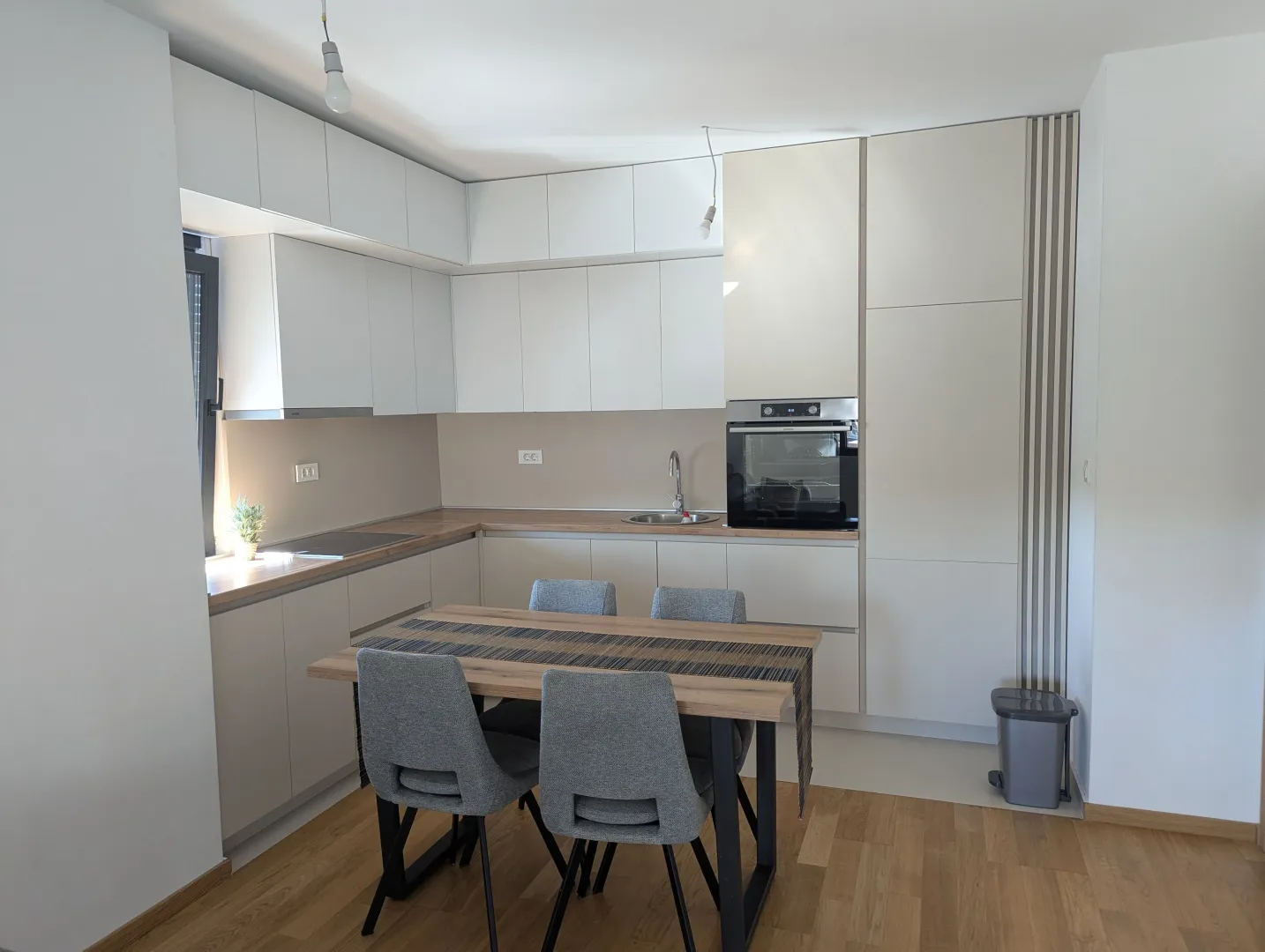 Modern kitchen with white cabinetry and a dining table with grey chairs.
