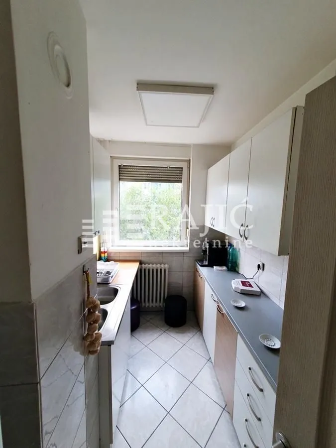 Small white kitchen with a window and cabinetry.