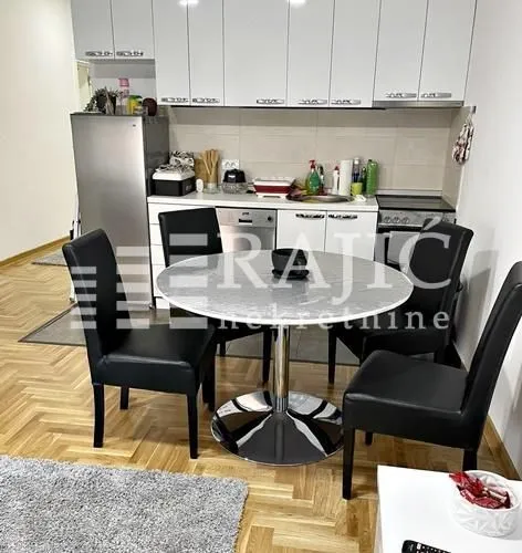Dining area connected to the kitchen with white cabinetry and a dining table with black chairs.