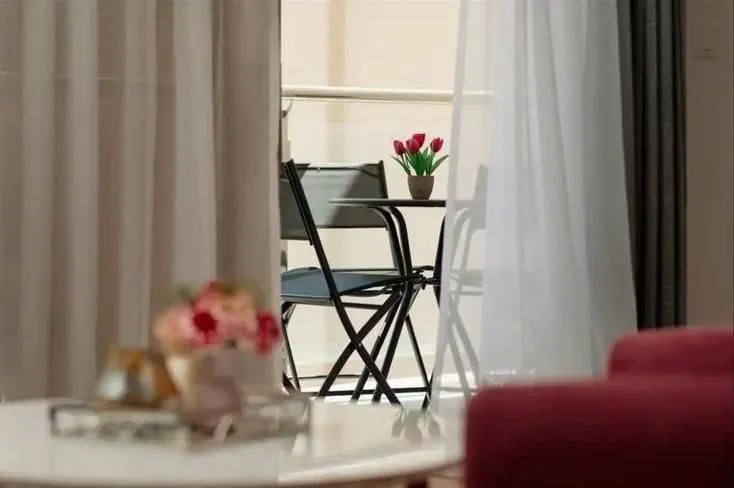 A view through the windows to a furnished balcony with a table and chairs.