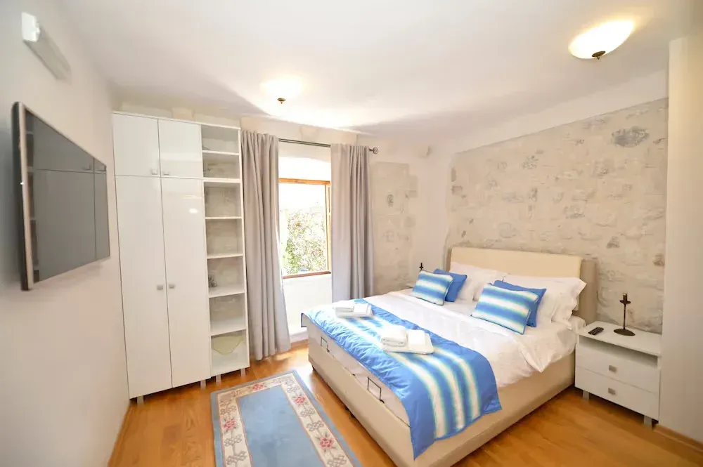 Furnished bedroom with a double bed, wardrobe, and stone wall feature.