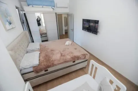 Furnished bedroom with a double bed, wardrobe, and TV. - image 11