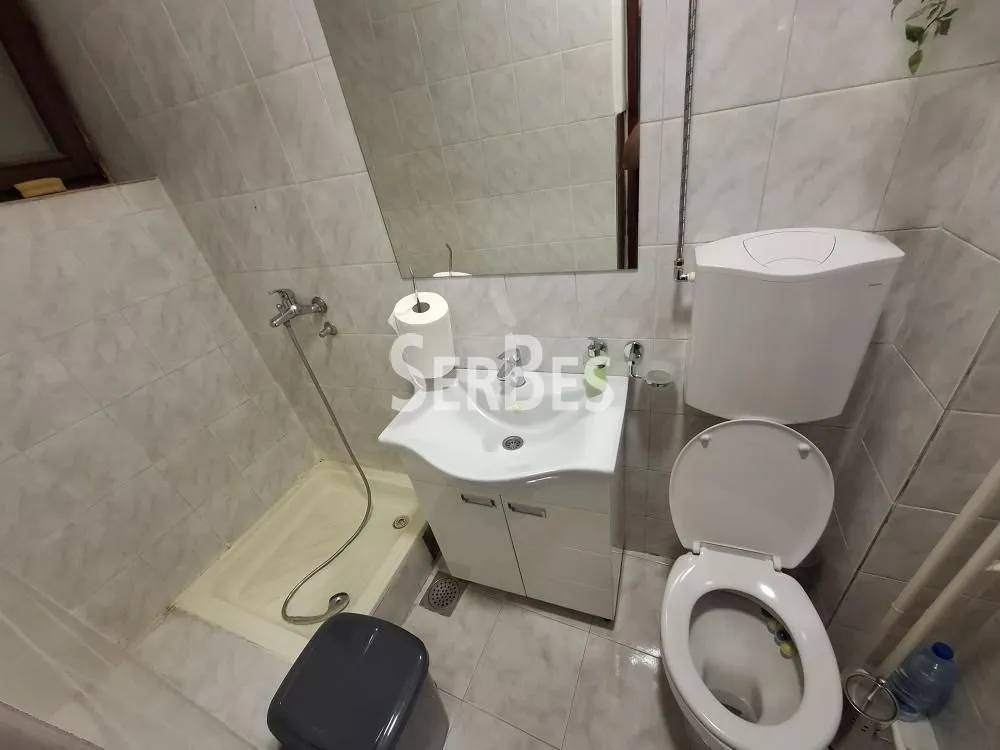 Kupatilo opremljeno tuš kabinom, umivaonikom i toaletom, obloženo keramičkim pločicama.
