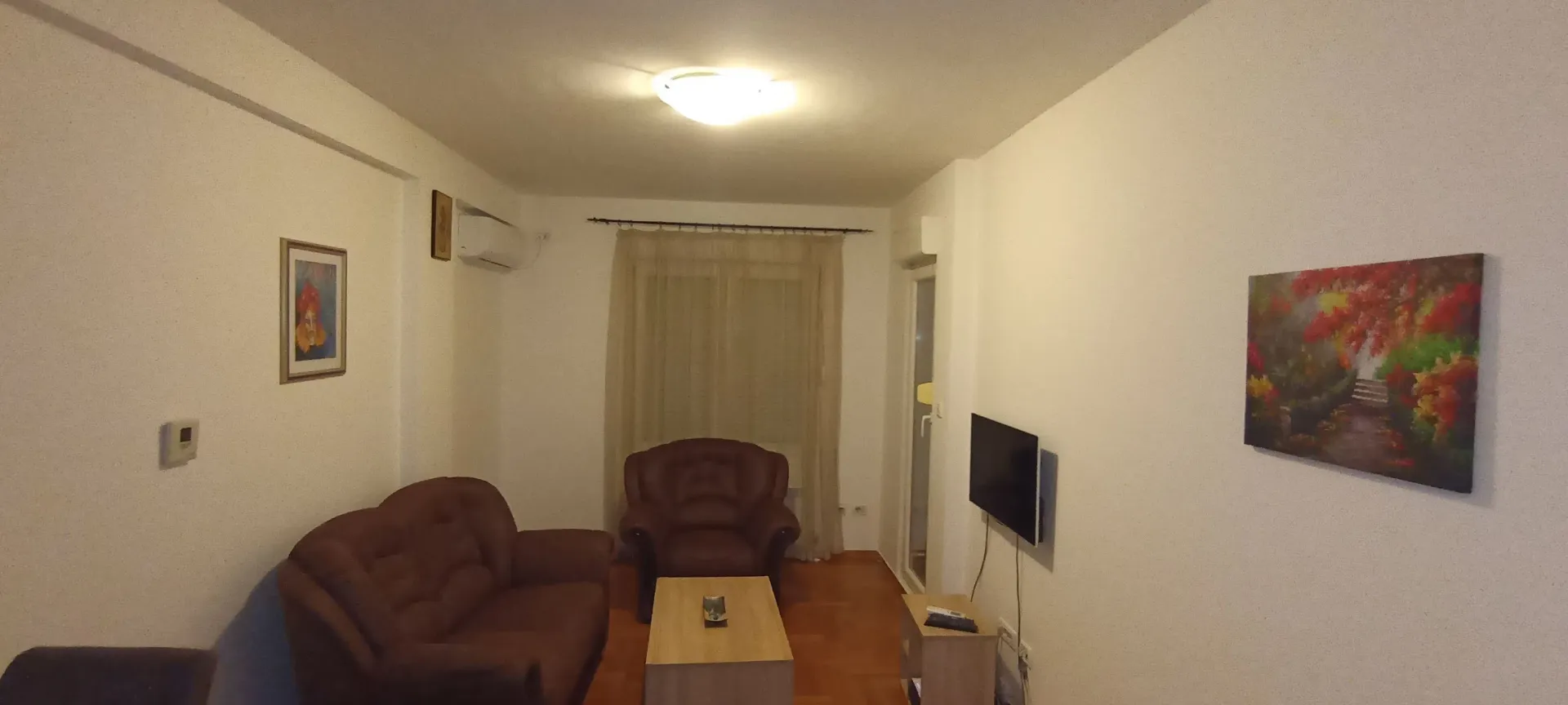 Simply furnished living room with a brown sofa set, coffee table, and a TV.