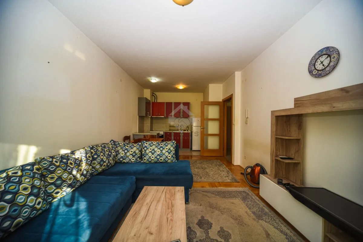 Living room with a sectional sofa and a view of the kitchen in the background.