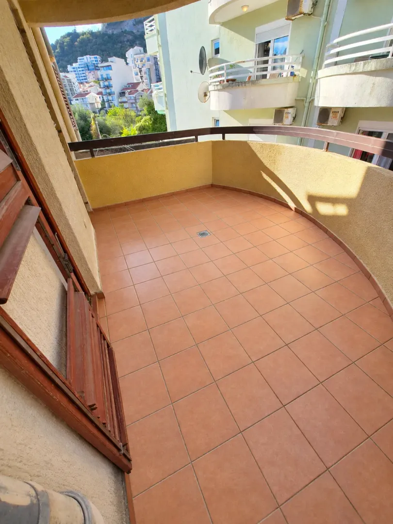 Spacious tiled terrace with a view of neighboring buildings and surroundings.