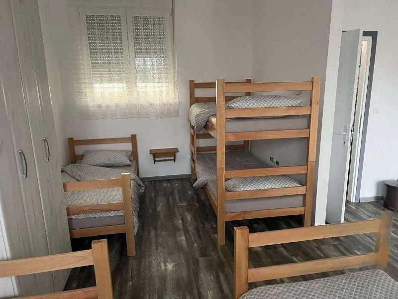 Bedroom with multiple wooden beds and a wardrobe.