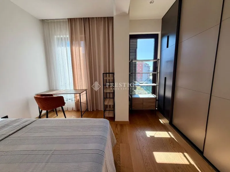 Furnished bedroom with a wardrobe, desk, and a window with curtains.